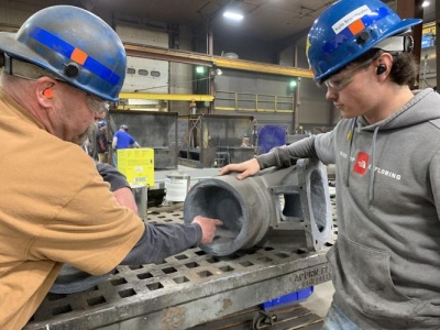 Randy Brenneman, left, a shop foreman for Beitzel Corporation, shows paid apprentice Kyle Broadwater, 18, a Northern High School student, how to apply ceramic lining to industrial pipe fittings. Photo Credit: Greg Larry, Cumberland Times-News.