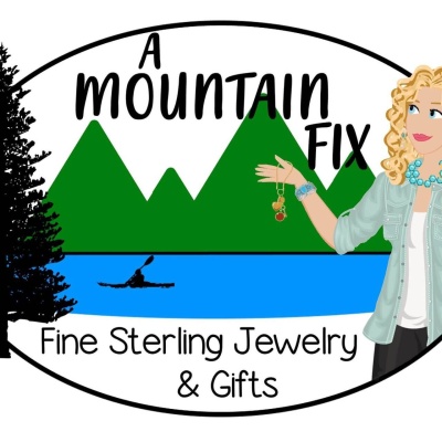 Logo: A Mountain Fix - fine sterling jewelry & gift (photo of a woman pointing to a pine tree, mountains, and a lake with a canoe gliding across it; logo colors: green, light blue, black