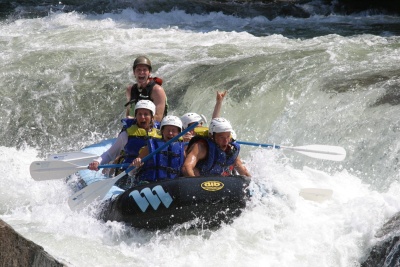 Photo courtesy of Demaree Inflatable Boats: multiple individuals in life jackets and helmets riding the rapids in a Demaree Inflatable Boat