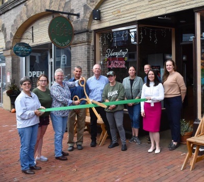 Men and women standing outside 206 Alder Bistro and Bar celebrating the business's 1 year anniversary with a ribbon cutting.