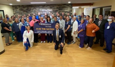 Staff of Garrett Regional Medical Center posing in the hospital's lobby with a sign WVU Medicine, Garrett Regional Medical Center, #9 in the Nation, 2024 Bernard A. Birnbaum, MD, Quality Leadership Study Award