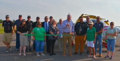 Men and women celebrating the ribbon cutting for Deep Creek Aviation, LLC at the Garrett County Airport.