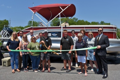 Men and women standing in front of a pontoon boat celebrating the ribbon cutting for Dockside Solutions