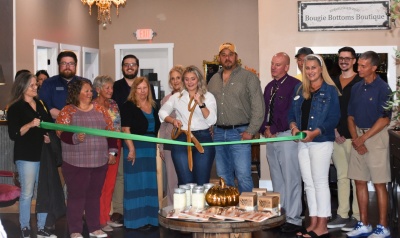 Men and women celebrating the grand opening of Bougie Bottoms Boutique with a ribbon cutting ceremony.