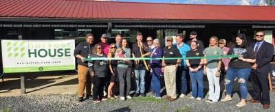 Men and women celebrating the grand opening of Harvest House DCL with a ribbon cutting.