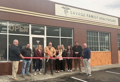 Men & women celebrating a ribbon cutting for Savage Family Healthcare