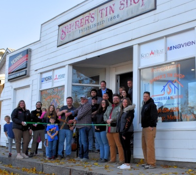 Men and women celebrating the ribbon cutting for Shirer's Tin Shop in Oakland.