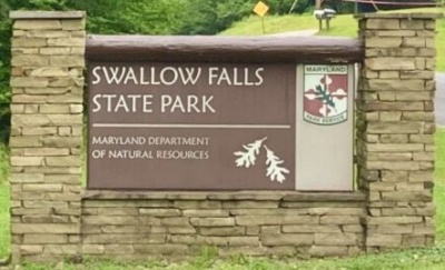 Swallow Falls State Park entrance sign. Maryland Department of Natural Resources. Sign if stone and brown board with the Maryland DNR logo in the upper right hand corner.