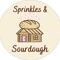 Logo: Sprinkles & Sourdough. Brown lettering on a cream background, with a house and loaf of bread in the middle of the logo.