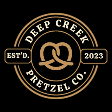 Circular Deep Creek Pretzel Co. logo featuring a stylized pretzel in the center, with “Deep Creek” above, “Pretzel Co.” below, and “Est’d. 2023” on either side.