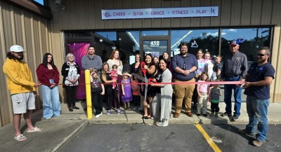 Photo: People celebrating the new location of Cosmic Cheer with a ribbon cutting.