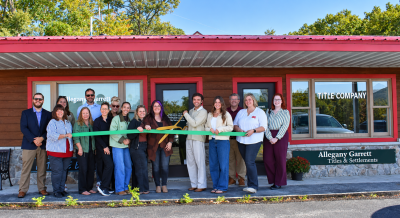 epresentatives of Allegany Garrett Titles & Settlements and community members gather outside the business for a ribbon-cutting ceremony, holding a green ribbon in front of the building. Photo courtesy of Garrett County Chamber of Commerce.